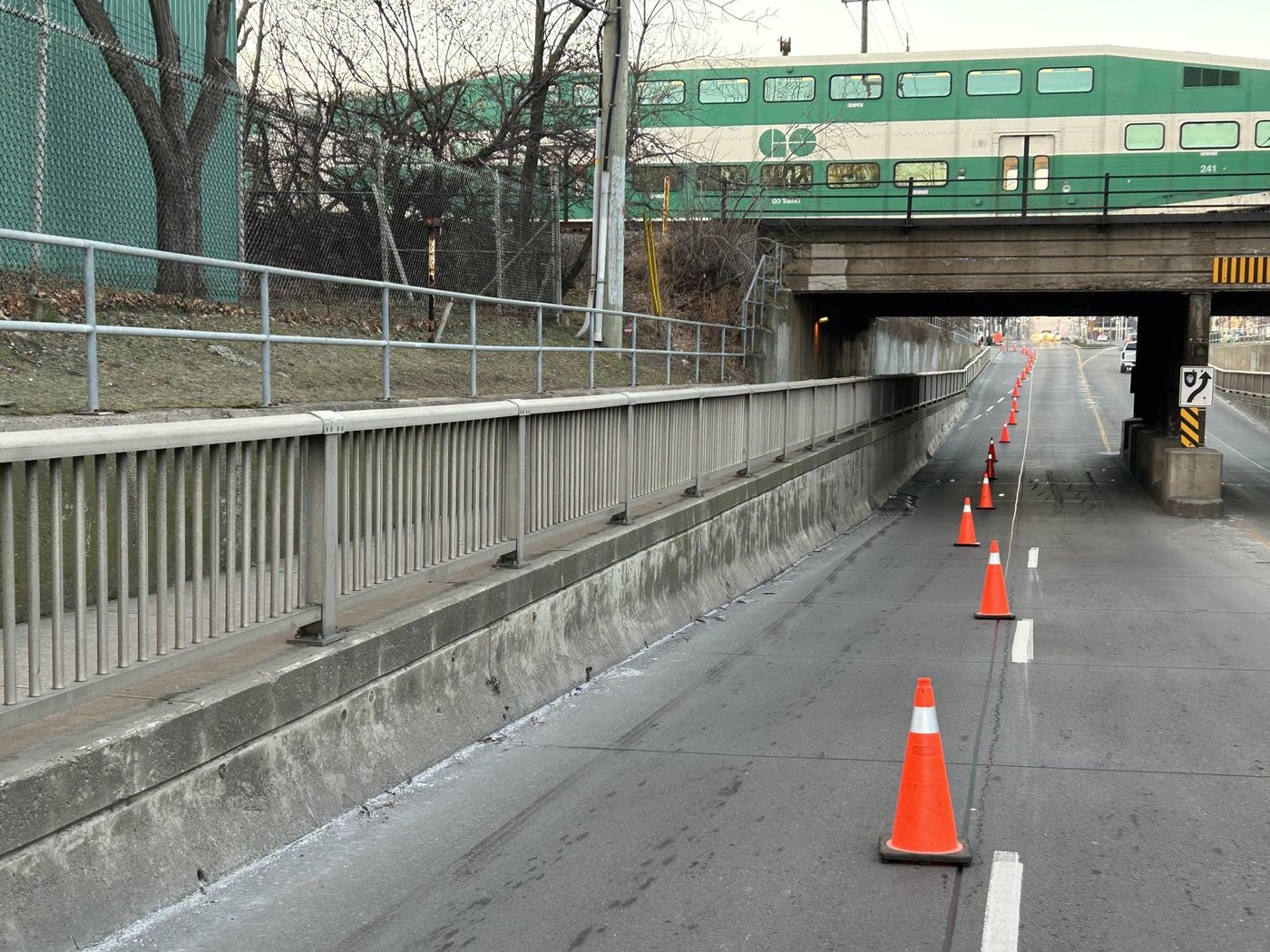 GO train crossing a rail overpass above retaining walls on a Hamilton road underpass